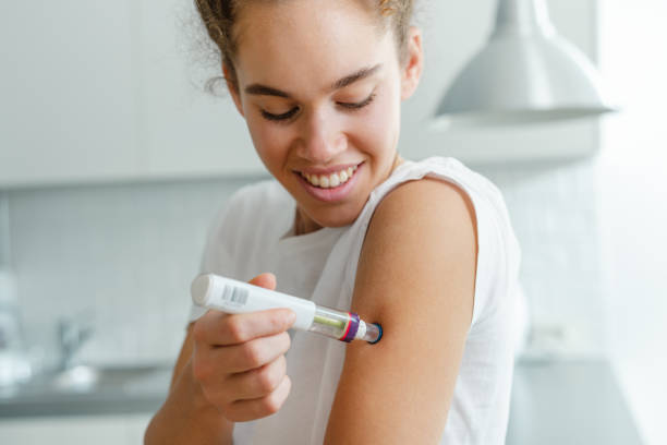 istock Young woman using an injector pen in a modern kitchen setting 2195158145