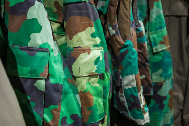 istock Camouflage green and brown military uniforms in a warehouse.. 2195158980