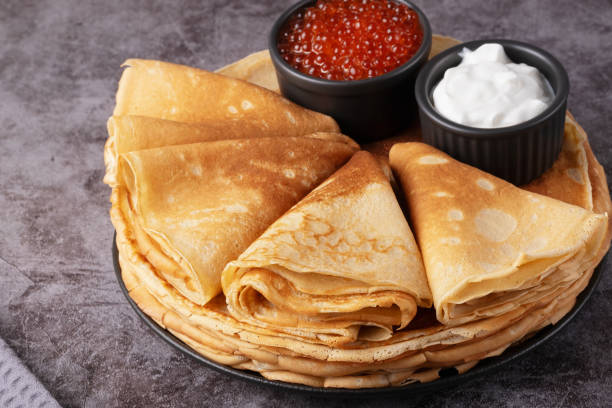 istock Delicious stack of golden pancakes served with cream and caviar on a rustic table 2195159067