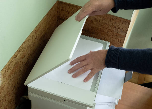 istock Men's hands put the document sheet in the scanner 2195159261