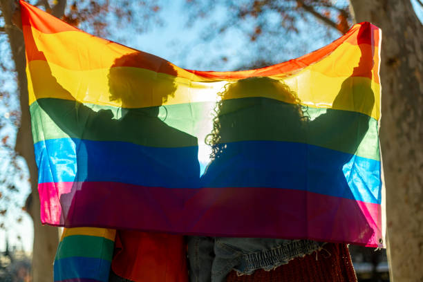istock Two people holding a lgbt flag behind their backs 2195166182