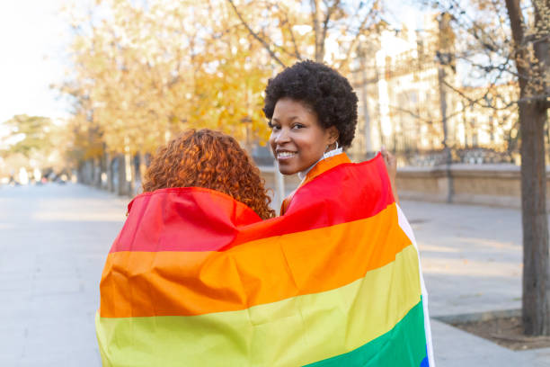 istock Two women holding rainbow flag smiling and looking at camera 2195166203