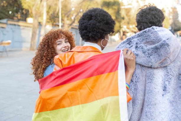 istock Young women holding lesbian pride flag, walking and looking back at camera 2195166213
