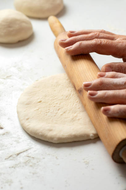 istock Rolling pin on dough on white kitchen table with wheat flour 2195169958