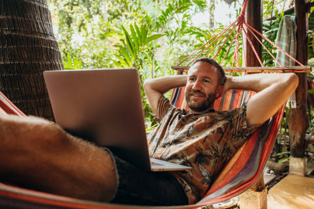 istock Man Relaxing in Hammock with Laptop in Tropical Setting 2195171451