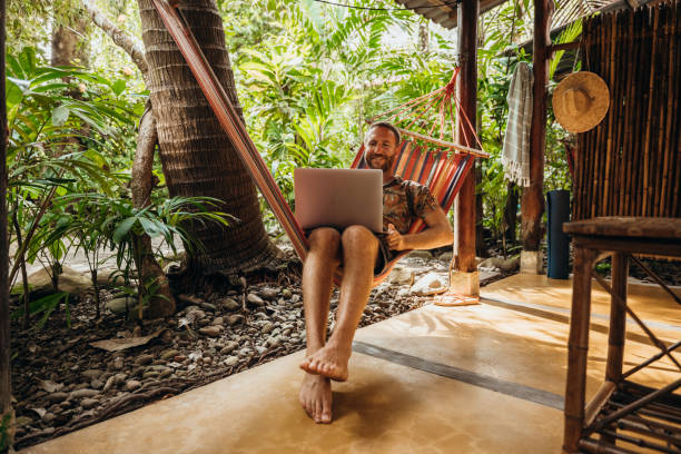 istock Man Relaxing in Hammock with Laptop in Tropical Setting 2195171888