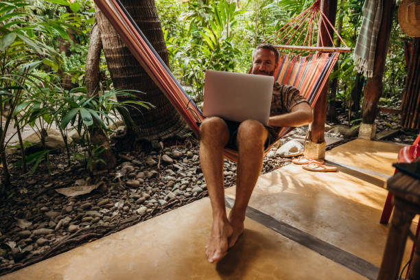 istock Man Relaxing in Hammock with Laptop in Tropical Setting 2195172086