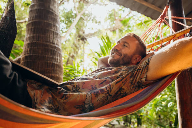 istock Man Relaxing in Hammock Working on Laptop in Tropical Setting 2195172271