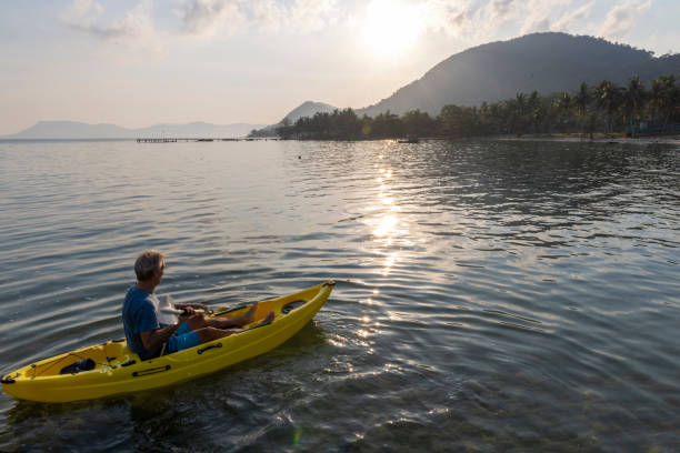 istock Man paddles kayak towards mountains at sunrise 2195172929