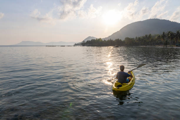 Man paddles kayak towards mountains at sunrise, Phu Quoc Island