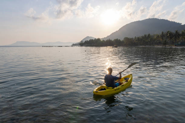 istock Man paddles kayak towards mountains at sunrise 2195173021
