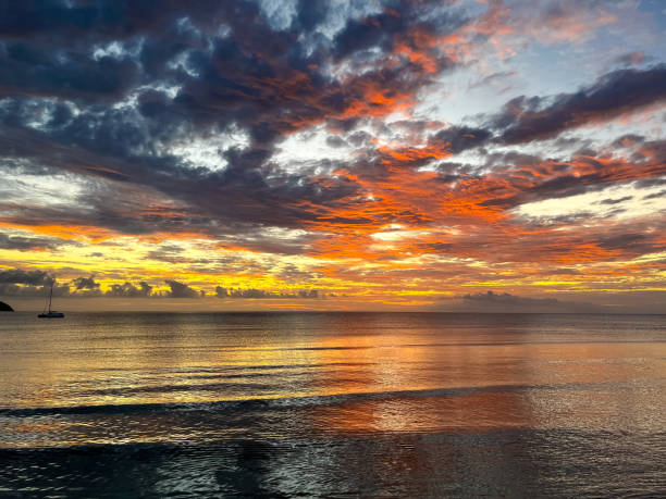 istock A tropical island sunset unfolds with vibrant colors, casting a dramatic glow over the ocean as dark clouds drift across the sky 2195175208