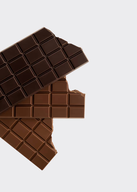 A visually appealing composition featuring stacked milk and dark chocolate bars with broken edges against a clean white background. The image emphasizes the rich texture and smooth surface of high-quality chocolate, making it perfect for branding, packaging, advertising, and editorial projects related to fine confectionery, luxury sweets, and gourmet desserts.