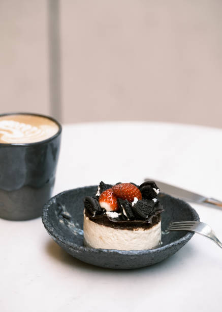 Elegant mini cheesecake topped with fresh strawberries, chocolate drizzle, and crumbled cookies on a ceramic plate, gourmet dessert presentation, fine dining patisserie, luxury café sweet treat for branding