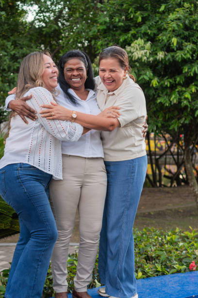istock Three happy female colleagues hugging each other in a park 2195190388