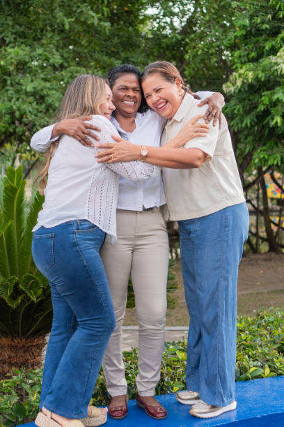 istock Three happy female friends embracing in a park 2195190389