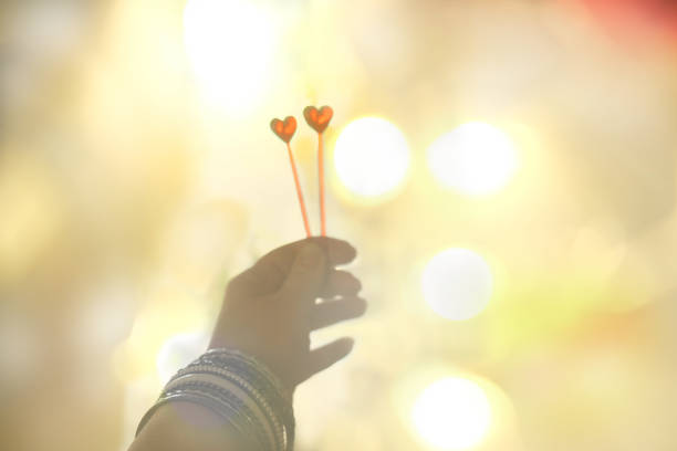 Hand holding two hearts, sunlight, blurred background with copy space. Love, peace, praying, protection, volunteering,  healthcare and humanity concept