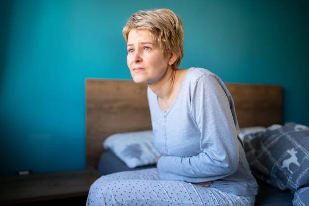 istock Middle-aged woman is sitting in her bed while having stomachache 2195191744