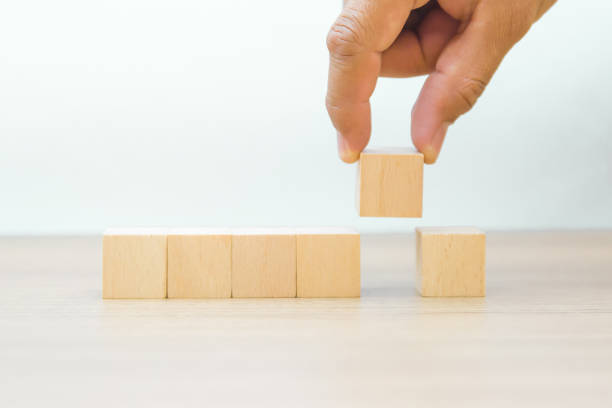 istock Hand choose cube wooden toy blocks are stacked in a pyramid shape without graphics 2195200103