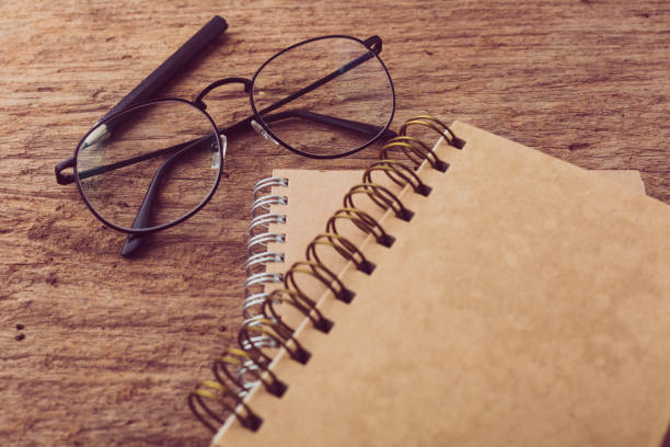 istock Notebook with glasses and pencil on wooden background 2195202659