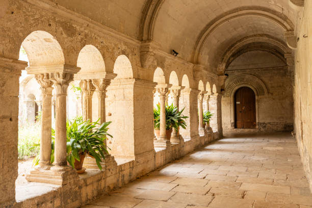 Lower part of the majestic interior of the cloister of Ambronay Abbey illuminated by night. This photo was taken at the Notre Dame d'Ambronay Abbey famous local monument in the French village of Ambronay, in the Ain department in the Auvergne-Rhone-Alpes region.