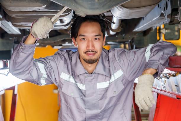 istock Mechanic smiling under car lift with tools in hand, emphasizing confidence, professionalism, and dedication to quality in automotive repair at a trusted small business garage. 2195204442