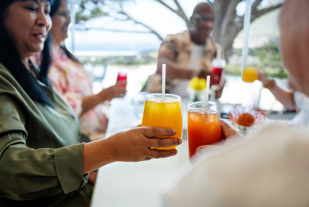 Group of senior friends sitting at a table and toasting with drinks at a restaurant