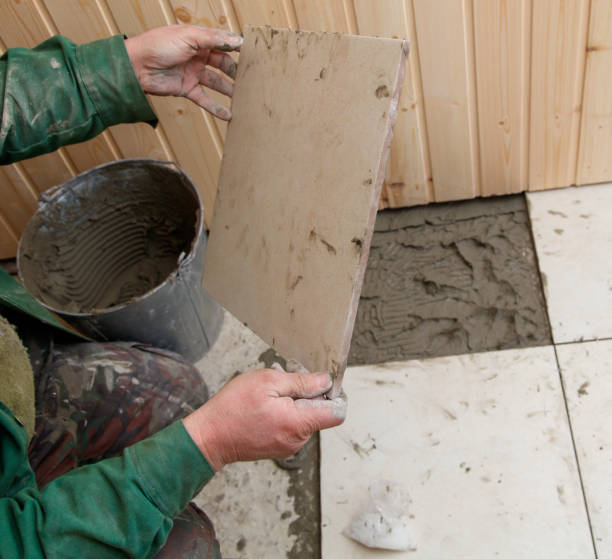istock A man is holding a tile in his hand while standing on a tiled floor 2195210088