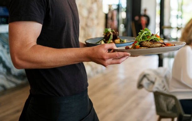 Waiter serving dish to guests at a restaurant