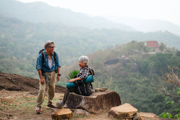 istock Elderly friends are sitting and talking on a mountain with a beautiful view. 2195210325