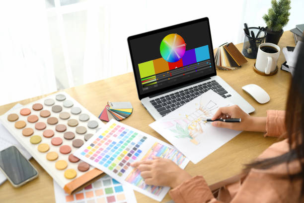istock Female designer sketching an interior layout and consulting various color palettes on her laptop 2195212106
