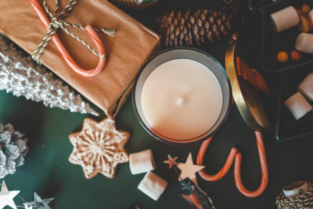 Festive Christmas composition with holiday decorations, red cup of tea, candy canes, marshmallows, and gifts on green background