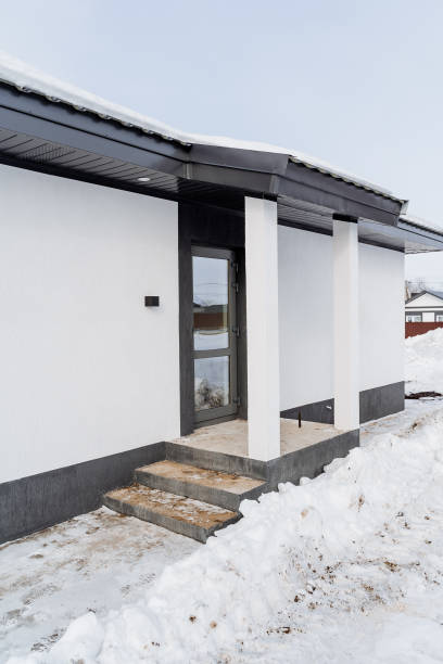 istock A splendid and beautiful white house featuring a charming porch along with elegant stairs is entirely surrounded by pristine, untouched snow, creating a truly stunning winter scene 2195217841