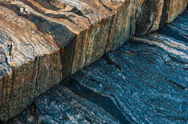 Colorful rock formations by the water's edge during daylight display unique textures and patterns
