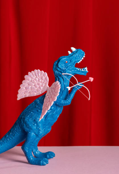 istock Blue dinosaur with pink wings with bow and arrow 2195219683