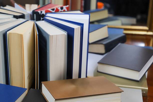 istock stack of books, close up. Open book on the table in library. Back to school concept. 2195222998