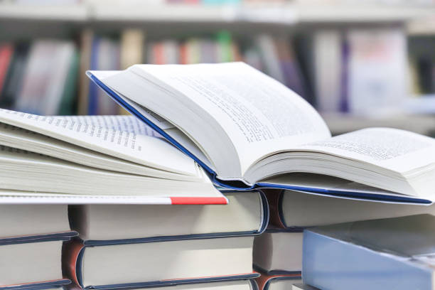 istock stack of books, close up. Open book on the table in library. Back to school concept. 2195223006