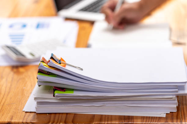 istock Paper documents are stacked on wooden desks at the workplace. 2195223482