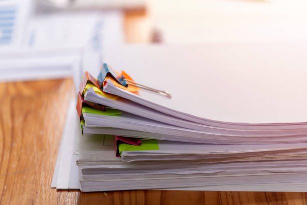 istock Paper documents are stacked on wooden desks at the workplace. 2195223483