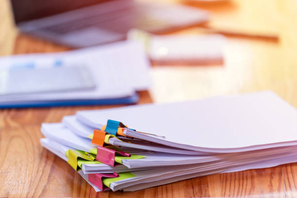 istock Paper documents are stacked on wooden desks at the workplace. 2195223550