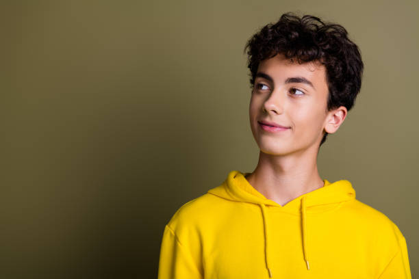 istock Young stylish boy in yellow hoodie on khaki backdrop with cheerful expression 2195227344