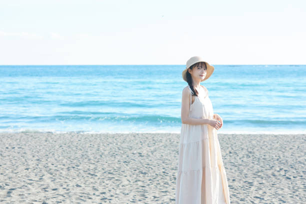 istock Young Asian woman strolling along the beach 2195227611