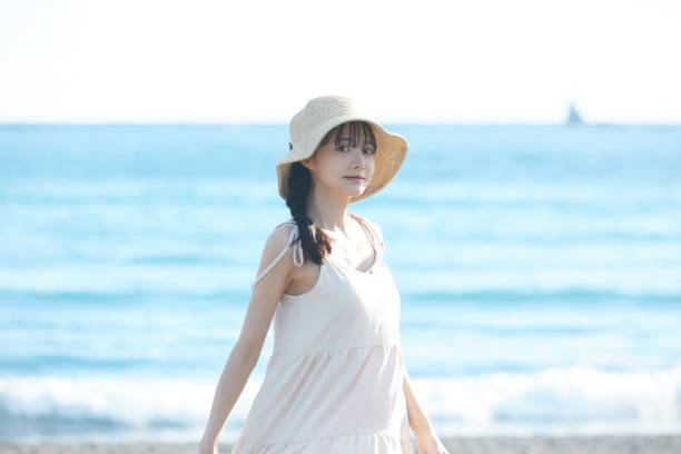 istock Young Asian woman strolling along the beach 2195227688
