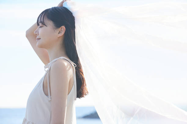 istock Young Asian woman strolling along the beach 2195228311