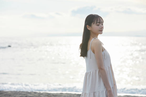 istock Young Asian woman strolling along the beach 2195228504