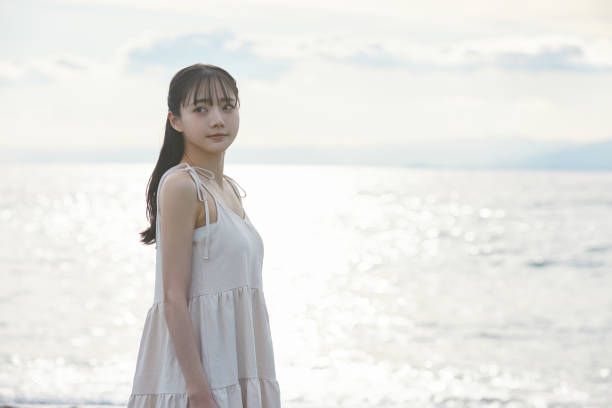 istock Young Asian woman strolling along the beach 2195228543