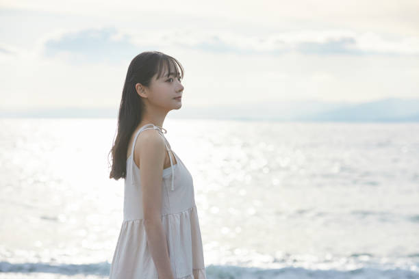istock Young Asian woman strolling along the beach 2195228547