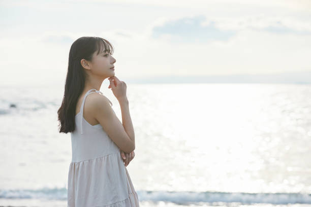 istock Young Asian woman strolling along the beach 2195228572