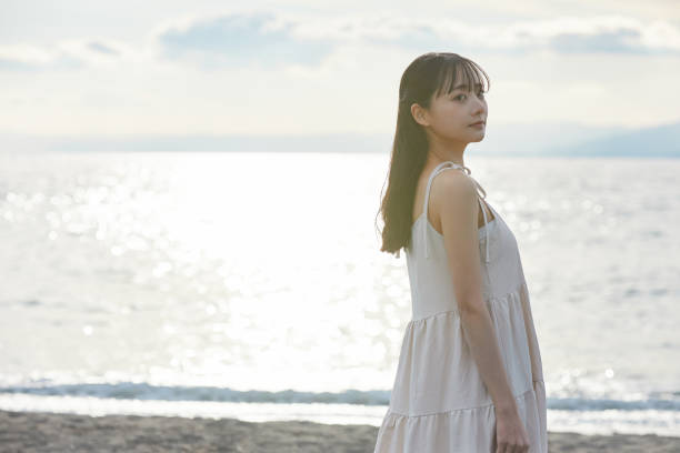istock Young Asian woman strolling along the beach 2195228600