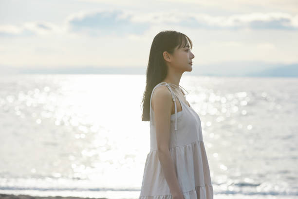 istock Young Asian woman strolling along the beach 2195228603
